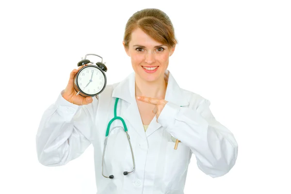 Uśmiechnięta kobieta lekarz palcem wskazującym na budzik — Zdjęcie stockowe
