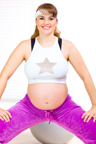 Sonriendo hermosa mujer embarazada haciendo gimnasia en la sala de estar — Foto de Stock