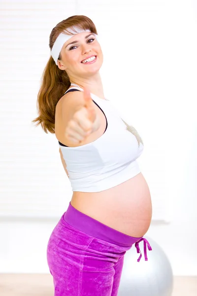 Sorrindo bela mulher grávida em sportswear mostrando polegares para cima gesto — Fotografia de Stock