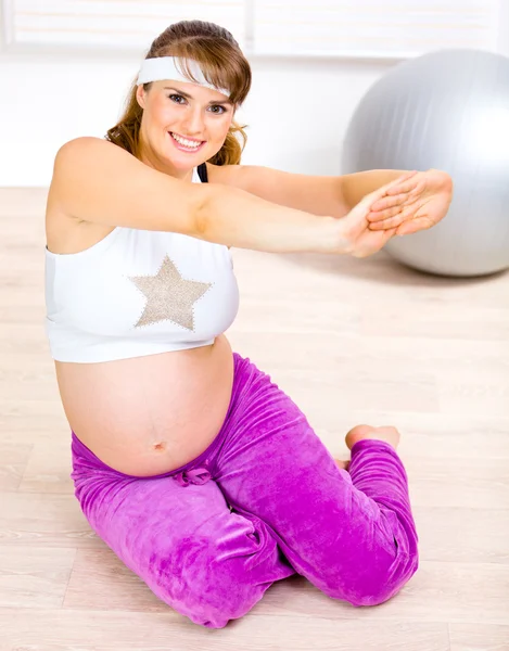 Smiling beautiful pregnant female doing fitness exercises at home — Stock Photo, Image