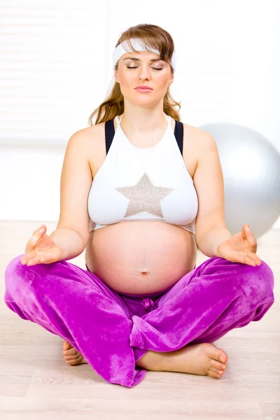 Konzentrierte schöne schwangere Frau macht zu Hause Yoga-Übungen auf dem Boden — Stockfoto