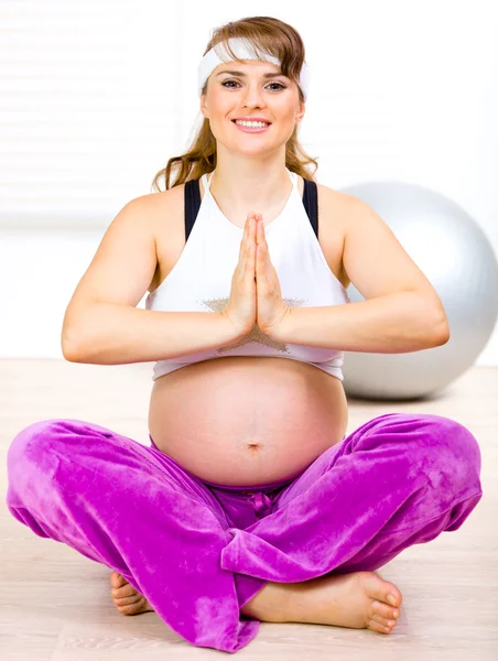 Sonriendo hermosa mujer embarazada haciendo ejercicios de yoga en el suelo en casa —  Fotos de Stock