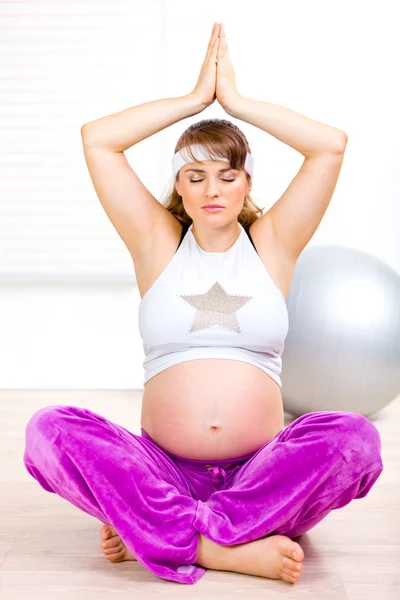 Hermosa mujer embarazada haciendo ejercicios de yoga en el suelo en casa —  Fotos de Stock