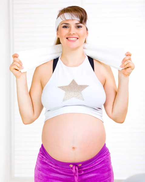 Χαμογελώντας όμορφη έγκυος γυναίκα σε αθλητικά ενδύματα, κρατώντας την πετσέτα γύρω από το ne — Φωτογραφία Αρχείου