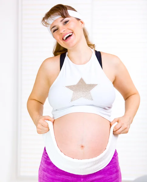 Boldog szép terhes nő a törülközőt körül a hasát, sportruházat — Stock Fotó