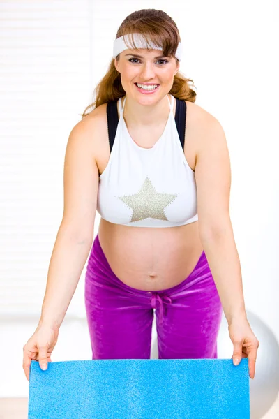 Lachende mooie zwangere vrouw oefening mat bedrijf in handen — Stockfoto
