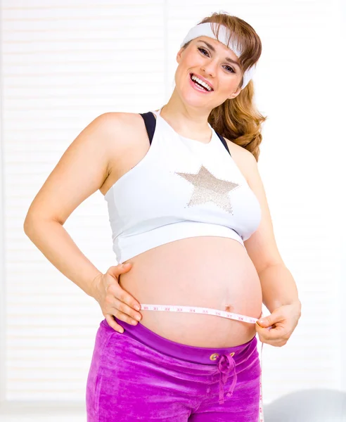 彼女の腹を測定美しい妊娠中の女性の笑みを浮かべてください。 — ストック写真