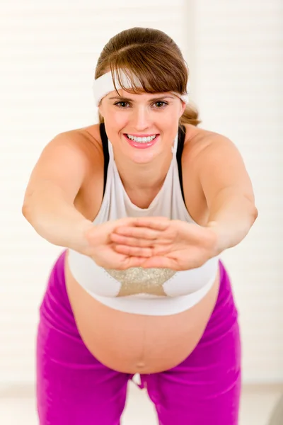 Улыбающаяся красивая беременная женщина делает упражнения дома — стоковое фото