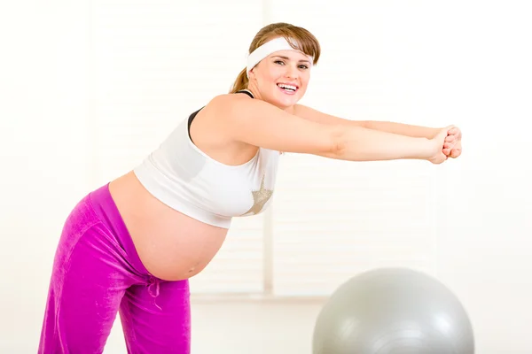Usmívající se krásná těhotná žena dělat gymnastiku doma — Stock fotografie