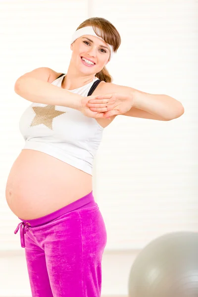 Smiling beautiful pregnant female making gymnastics at living room — Stock Photo, Image