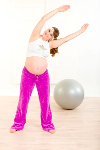 Улыбка прекрасная беременная женщина делает упражнения дома — стоковое фото
