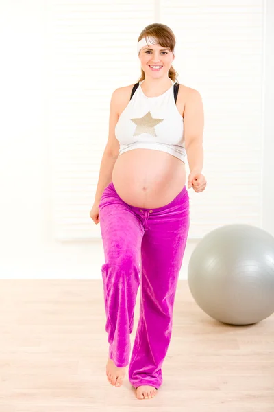 Посміхаючись красива вагітна жінка робить фізичні вправи вдома — стокове фото