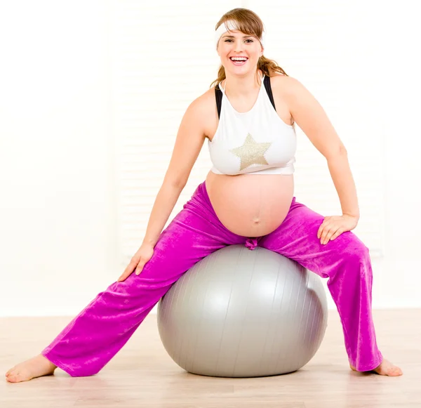 Pregnant female doing pilates exercises on gray ball — Stock Photo, Image