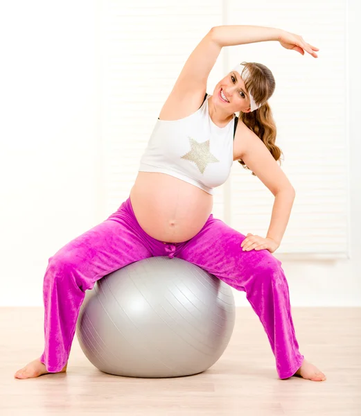 Mujer embarazada haciendo ejercicios de pilates en bola gris — Foto de Stock