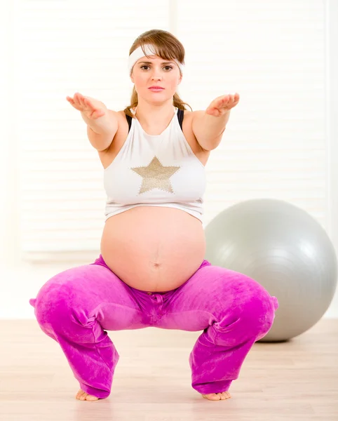 Gülümseyen güzel hamile kadın fitness egzersizleri oturma odasında yapıyor — Stok fotoğraf