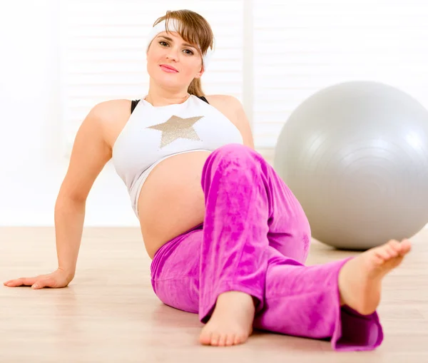 Sorrindo bela fêmea grávida fazendo ginástica na sala de estar — Fotografia de Stock