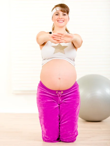 Sonriendo hermosa mujer embarazada haciendo ejercicios de fitness en la sala de estar — Foto de Stock