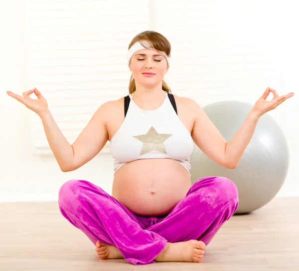 Mulher grávida bonita fazendo ioga no chão em casa — Fotografia de Stock