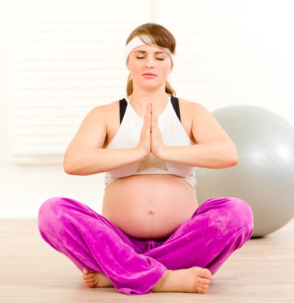 Mulher grávida atraente fazendo exercícios de ioga no chão em casa — Fotografia de Stock