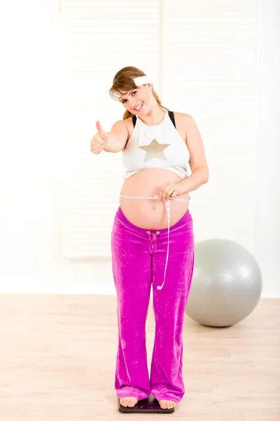 怀孕的女人站在体重秤上 — 图库照片