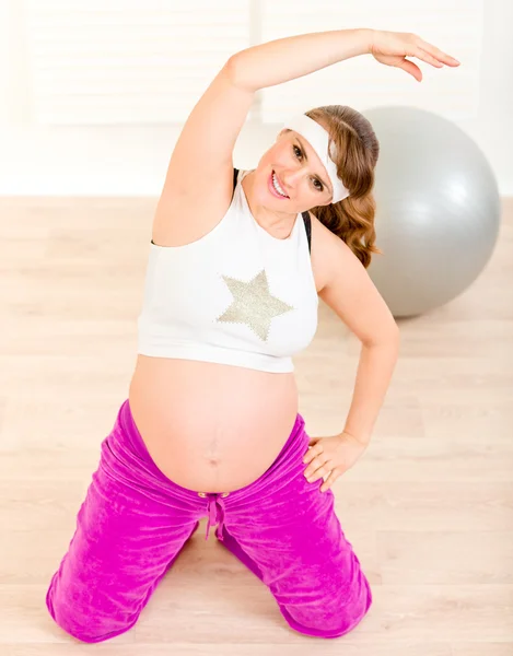 Sorrindo bela mulher grávida fazendo exercícios de fitness em casa — Fotografia de Stock