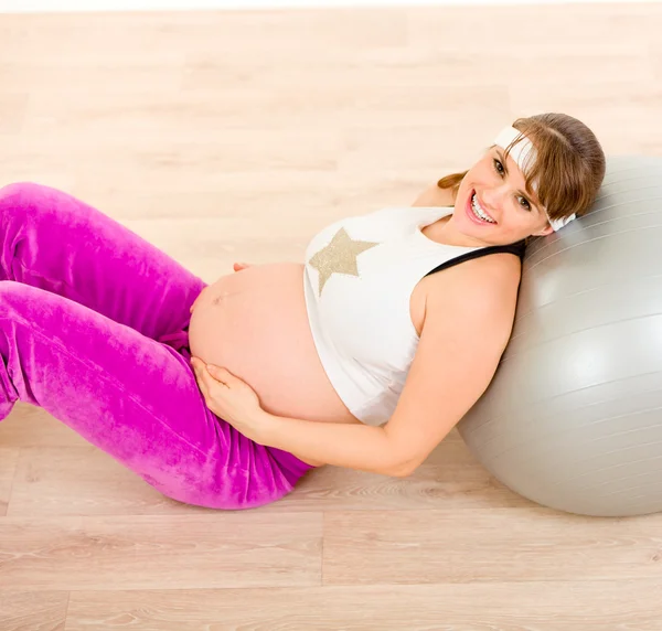 Uśmiechający się piękna kobieta w ciąży siedzi na podłodze i relaks — Zdjęcie stockowe