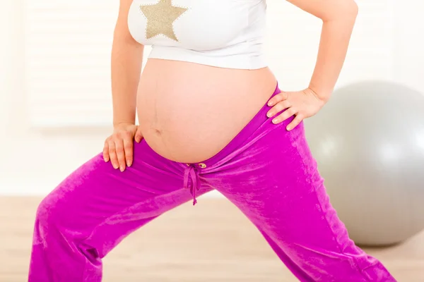 Těhotná žena, která dělá protahovací cvičení doma. detail. — Stock fotografie