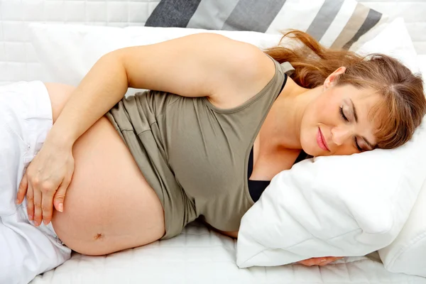 Красивая беременная женщина спит на диване — стоковое фото