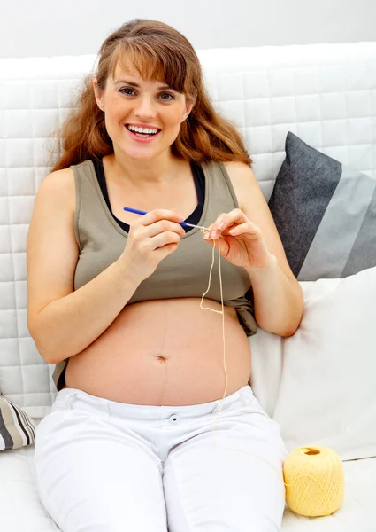 stock image Smiling beautiful pregnant female knitting for her baby