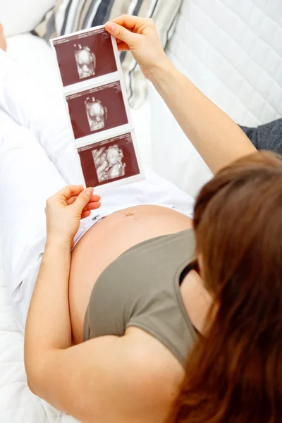 Gravid kvinna avkopplande på soffa och ser echo. närbild. — Stockfoto