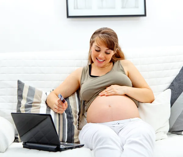 Sonriendo hermosa mujer embarazada utilizando la tarjeta de crédito para comprar desde Internet — Foto de Stock