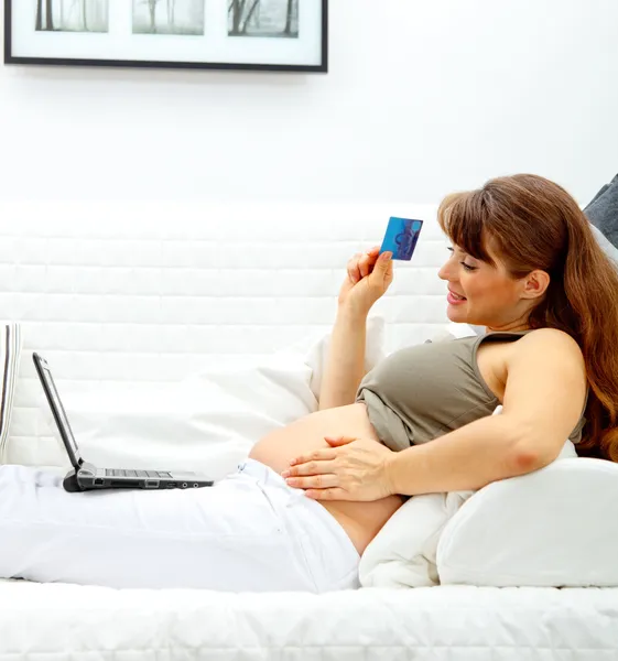 Lachende mooie zwangere vrouw met creditcard om te winkelen van internet — Stockfoto