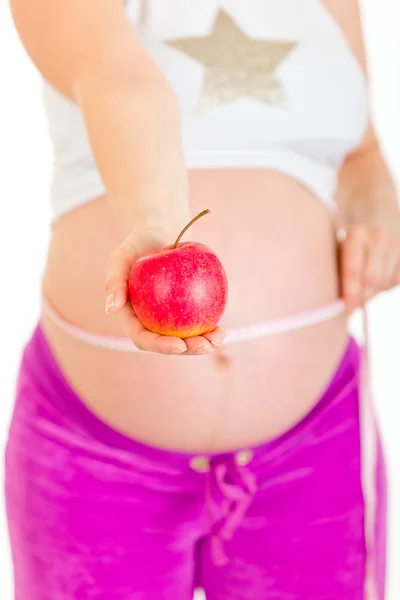 Donna incinta che misura la pancia e tiene in mano la mela. Primo piano . — Foto Stock