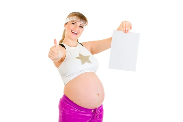 空の白い紙を保持し、gest 親指を示す妊娠中の女性の笑みを浮かべてください。 — ストック写真