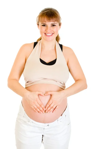 妊娠中の女性のおなかの上彼女の手で心を作るに笑みを浮かべてください。 — ストック写真