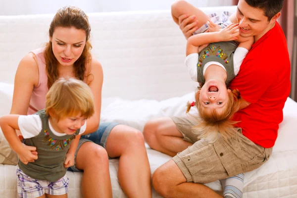 Родители веселятся с близнецами дочери на диване — стоковое фото
