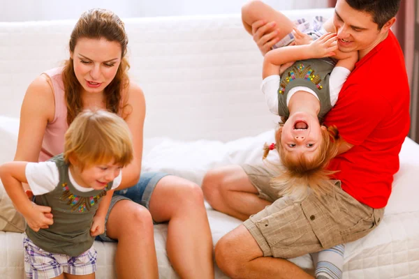 Los padres se divierten con las hijas gemelas en el sofá — Foto de Stock