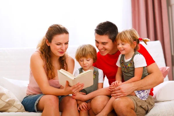 Mãe e pai lendo para gêmeos filhas — Fotografia de Stock