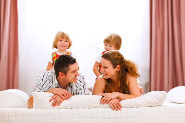 Rodinný portrét matka otec a dvojčata dcer na posteli — Stockfoto