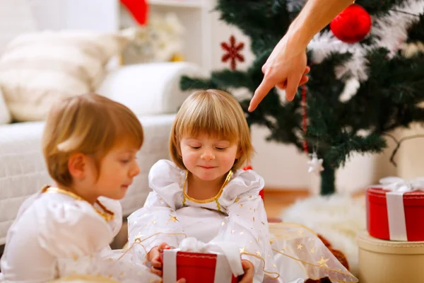 Hand eines Elternteils zeigt auf Geschenk für Zwillingsmädchen — Stockfoto