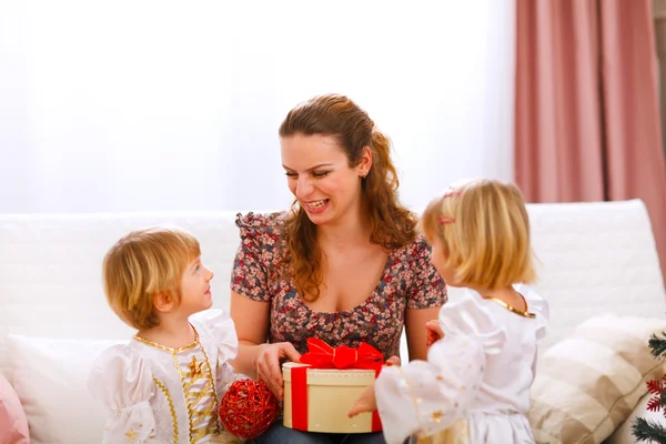 Счастливая мать держит в руках подарок своих дочерей близнецов — стоковое фото