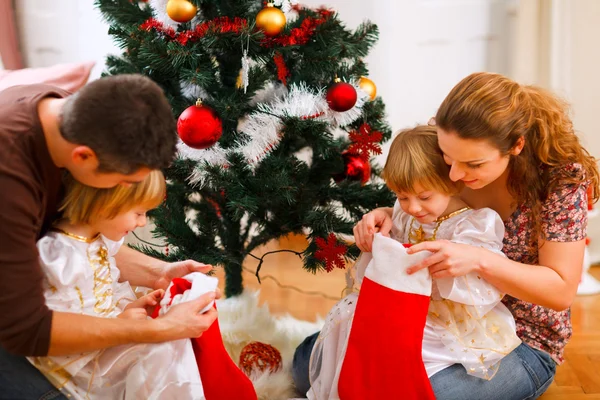Мама и папа смотрят с близнецами дочери внутри рождественских носков — стоковое фото
