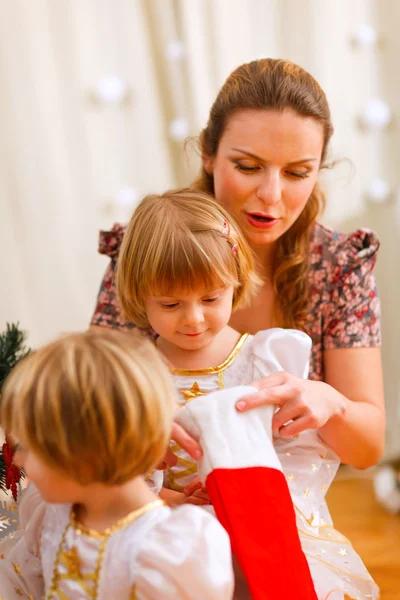 Mutter sucht mit Zwillingstöchtern in Weihnachtssocken — Stockfoto