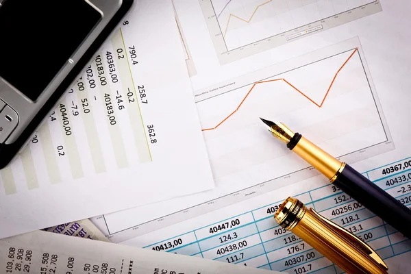 Mobiele telefoon, pen en financiële documenten met grafieken — Stockfoto
