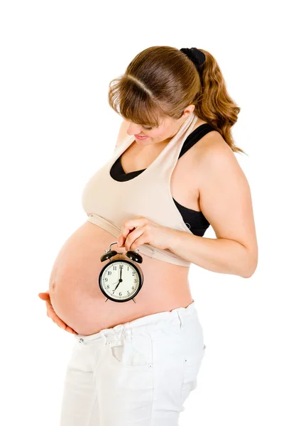 Pregnant woman holding alarm clock near her belly Royalty Free Stock Photos