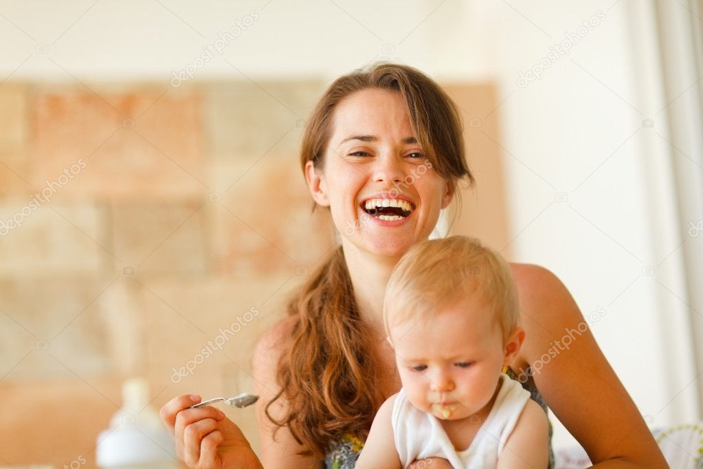 Portrait of laughing young mother feeding baby