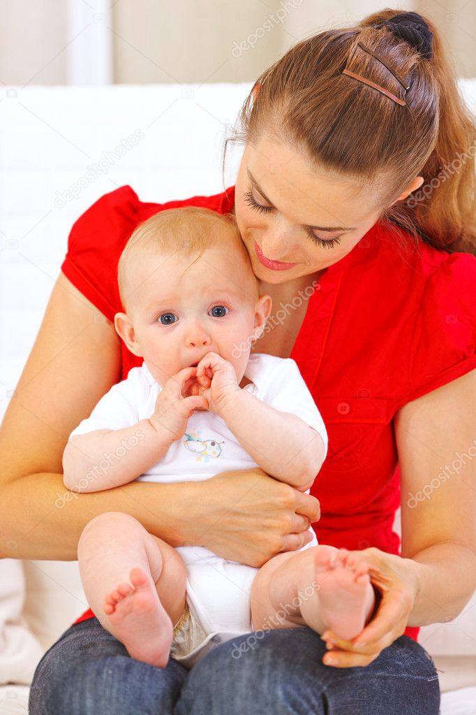 Baby putting his hands in mouth while sitting on mother laps