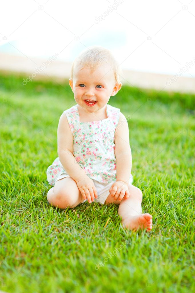 Happy baby sitting on grass