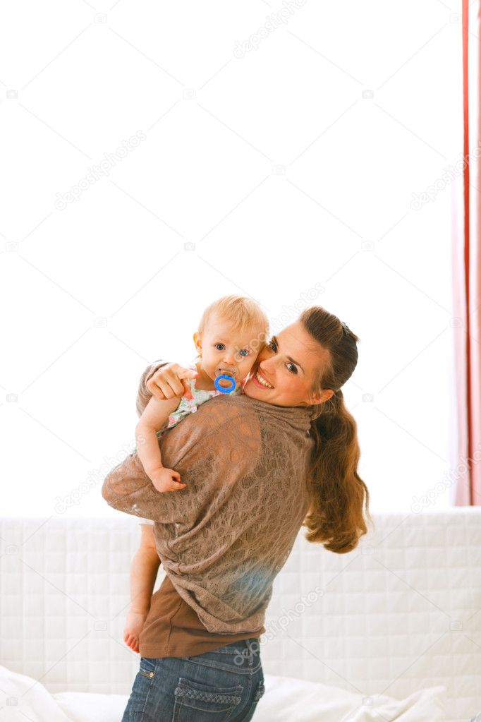 Young mom showing her baby something by pointing in camera