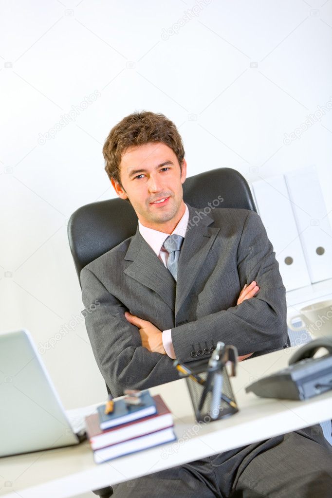 Portrait of modern businessman sitting at office desk